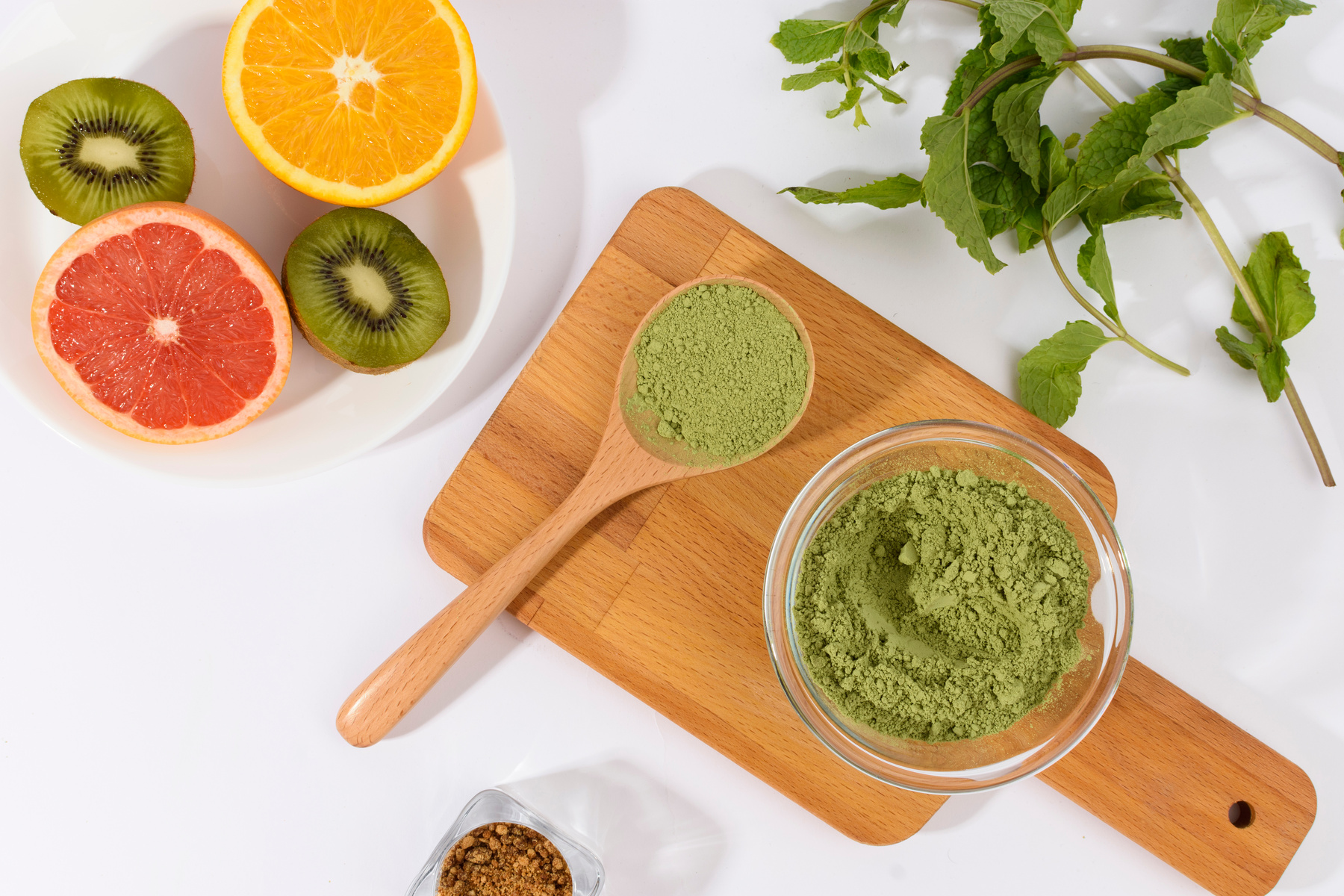 Bowl of Green Powder with Greens and Fruits Flatlay